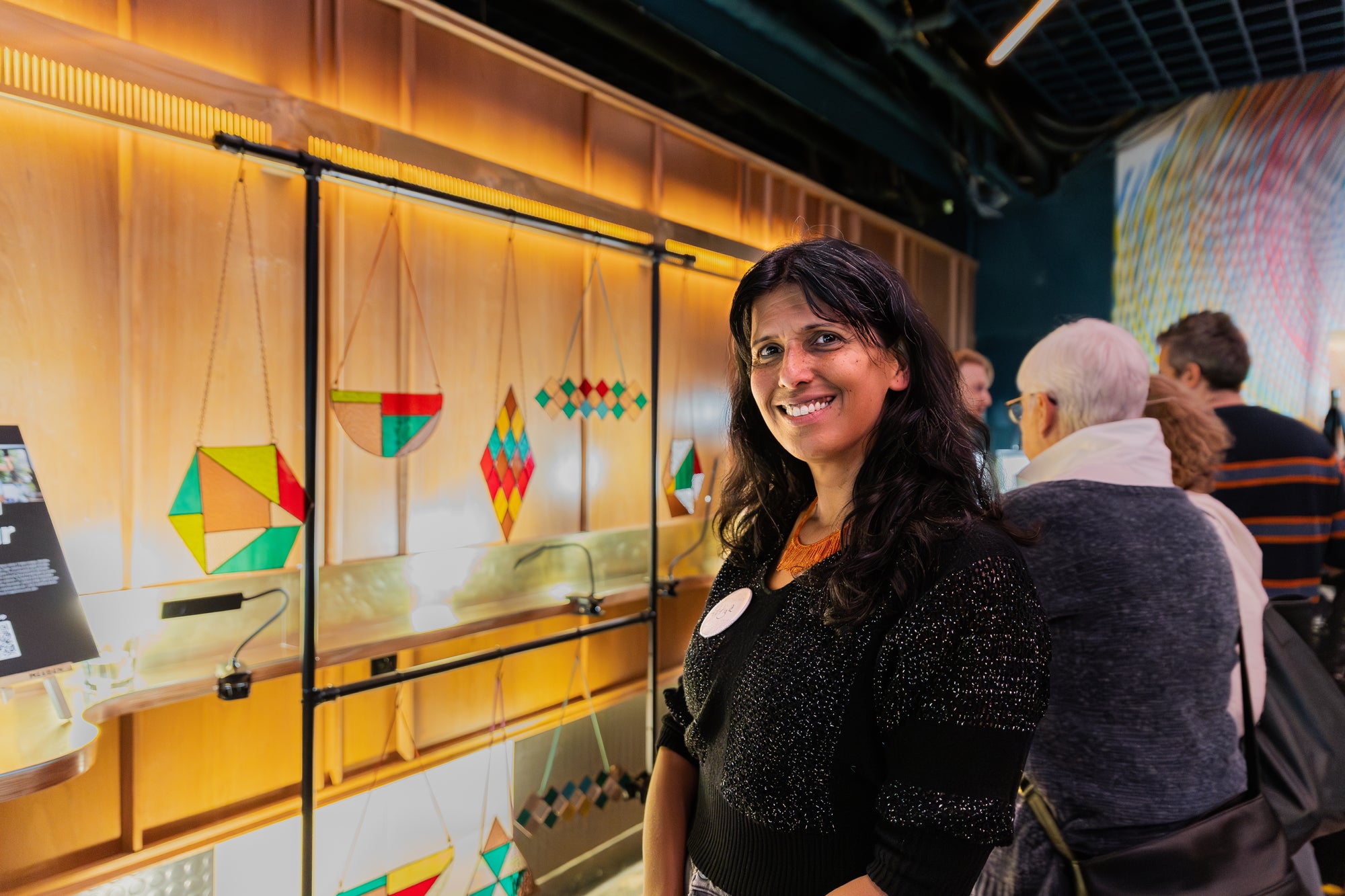 Artist Attiya Khan standing in front of her stained glass collection