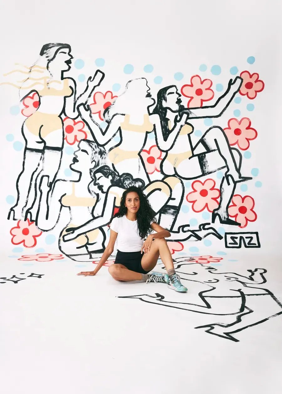 Sarah Alinia Ziazi sitting in front of her art