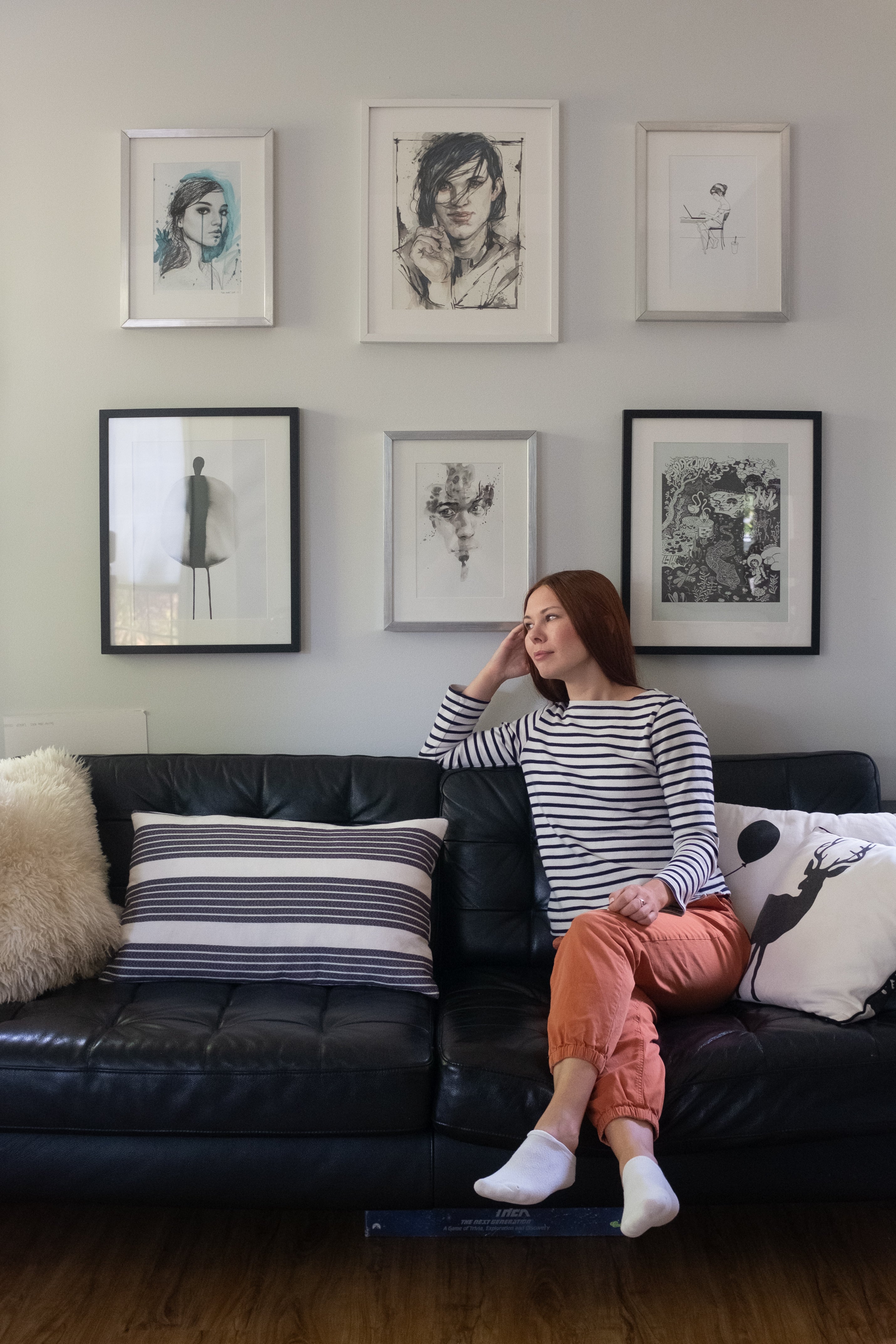 Designer Kat Lyadova sitting in front of a wall of hanging art